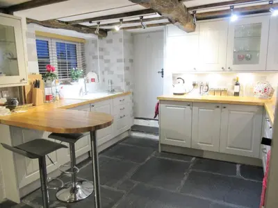 a kitchen with white cabinets and a wooden table at Garden Cottage in Threlkeld