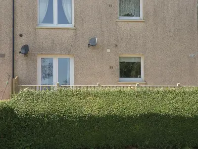 a building with windows and a hedge in front of it at Simply Suite in Castle Douglas