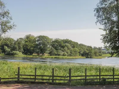 a fence in front of a river with trees at Simply Suite in Castle Douglas