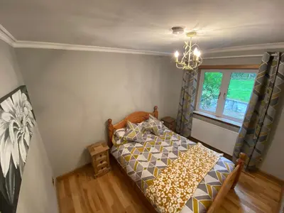 a bedroom with a bed and a window and a chandelier at Country Cottage Sleeps 6 w Hot Tub & Dog-Friendly in Moniaive