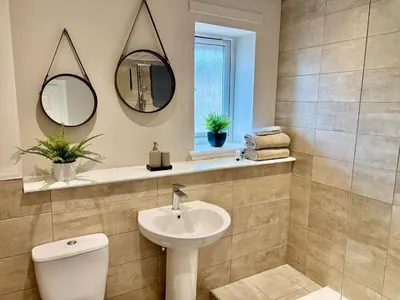 a bathroom with a sink and a toilet and mirror at Kincraig Apartment in Ayr