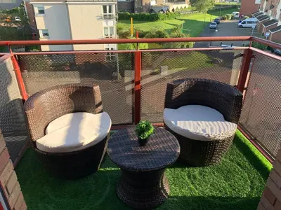 a balcony with two chairs and a table with a plant at Kincraig Apartment in Ayr