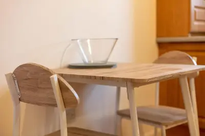a wooden table with two chairs and a laptop on it at Millbrae Residence - Donnini Apartments in Ayr