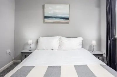 a bedroom with a white bed with two lamps at Millbrae Residence - Donnini Apartments in Ayr