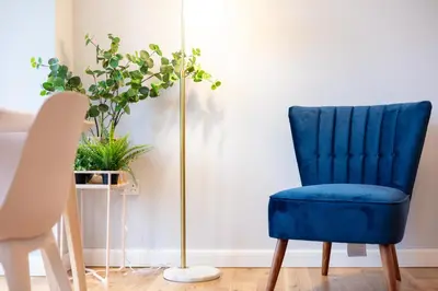 a blue chair next to a floor lamp at Millbrae Residence - Donnini Apartments in Ayr
