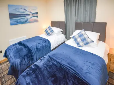 two beds in a room with blue and white at Uplands in Dalbeattie