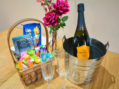 a bottle of wine and a basket of candy and flowers at Uplands in Dalbeattie