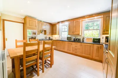 a large kitchen with wooden cabinets and a wooden table at Briarwood House in Keswick