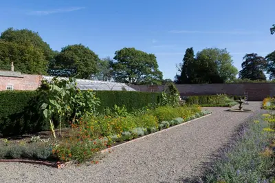 a garden with a gravel path and flowers at Netherby Hall in Carlisle