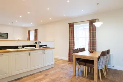 a kitchen with white cabinets and a table and chairs at Netherby Hall in Carlisle