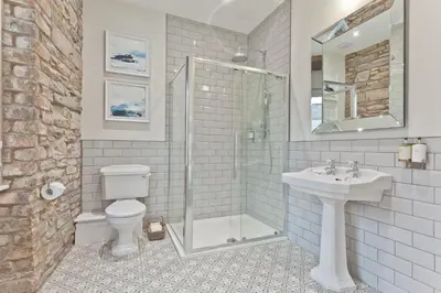 a bathroom with a shower and a toilet and a sink at Tithe Barn - Self Check In Hotel in Cockermouth