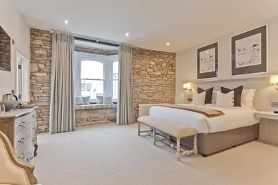 a bedroom with a large bed and a stone wall at Tithe Barn - Self Check In Hotel in Cockermouth