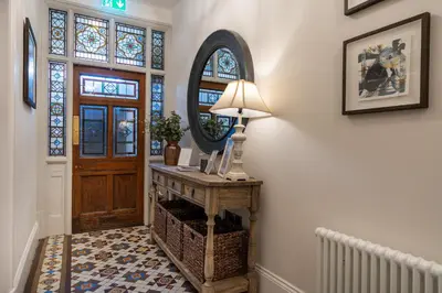 a hallway with a table with a lamp and a mirror at Tithe Barn - Self Check In Hotel in Cockermouth