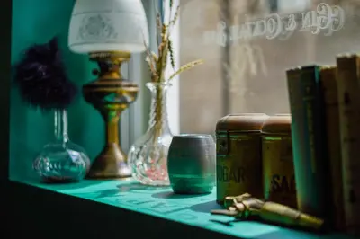 a table with books and vases and a lamp at Tithe Barn - Self Check In Hotel in Cockermouth