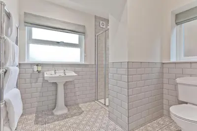 a white bathroom with a sink and a toilet at Tithe Barn - Self Check In Hotel in Cockermouth