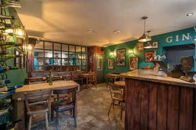 a restaurant with green walls and wooden tables and chairs at Tithe Barn - Self Check In Hotel in Cockermouth