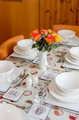 a table with white plates and flowers in a vase at Doonans Cottage in Maybole