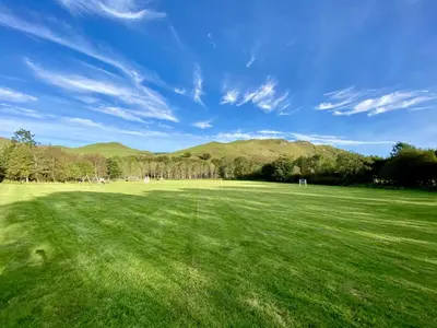 a large green field with mountains in the background at Doonans Cottage in Maybole