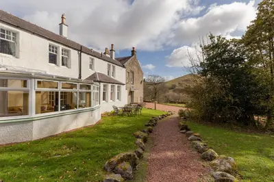 a house with a grass yard next to a building at Balcraig House in Maybole