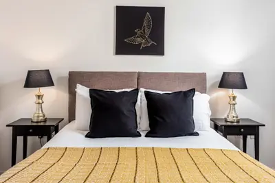 a bedroom with a bed with black pillows and two lamps at Walker Suite No53 - Donnini Apartments in Kilmarnock