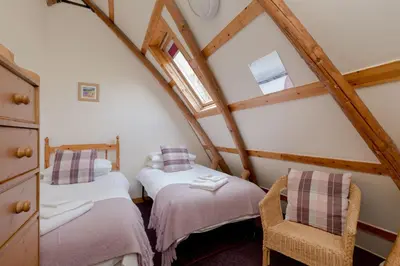 a attic room with two beds and a window at Rabbie Burns Lodge in Maybole