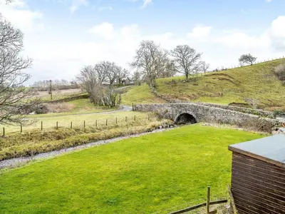 a stone bridge over a field with a tunnel at Branthwaite Cottage in Caldbeck