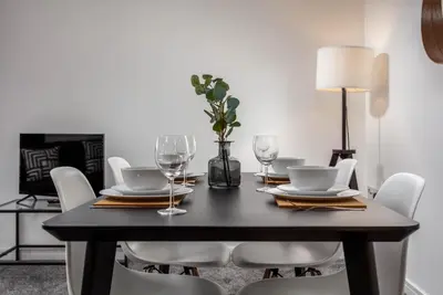 a black dining room table with white chairs and a lamp at Walker Suite No73 - Donnini Apartments in Kilmarnock