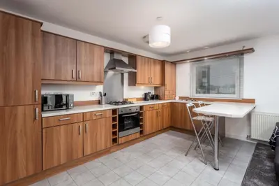 a kitchen with wooden cabinets and a table in it at Walker Suite No73 - Donnini Apartments in Kilmarnock