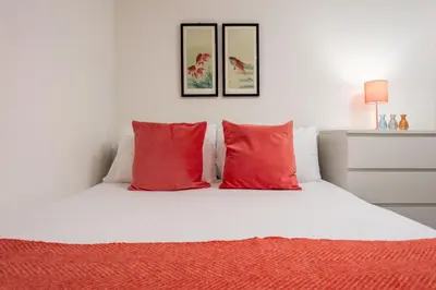 a bedroom with a white bed with red pillows at Walker Suite No73 - Donnini Apartments in Kilmarnock