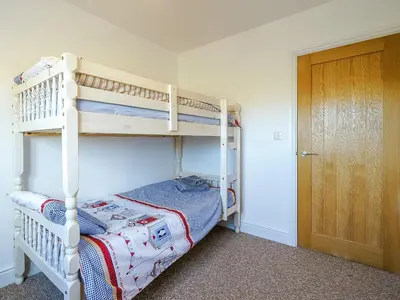 a bedroom with two bunk beds and a door at Seacote Gardens in St Bees
