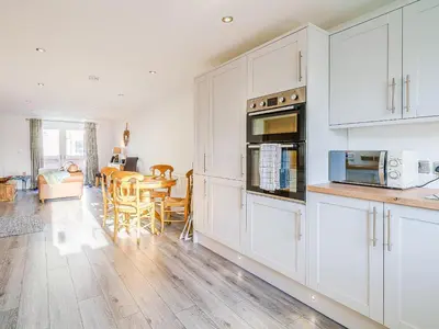 a kitchen with white cabinets and a dining room at Seacote Gardens in St Bees