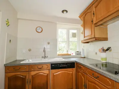 a kitchen with wooden cabinets and a sink at Fell Foot in Holmrook