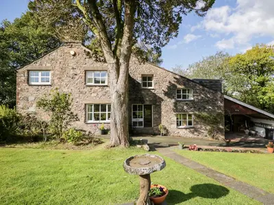 a stone house with a tree in front of it at Fell Foot in Holmrook