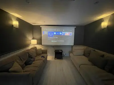 a living room with a couch and a large screen at Golden Crown exclusive use spa venue in Tarbolton