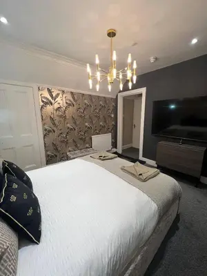 a bedroom with a large white bed and a chandelier at Golden Crown exclusive use spa venue in Tarbolton