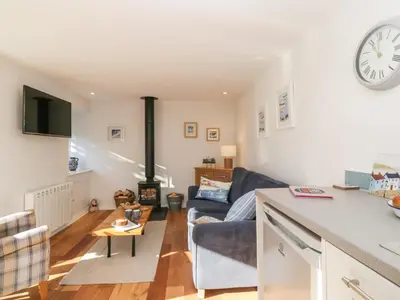 a kitchen and living room with a couch and a clock at Old Kiln Cottage in Dumfries