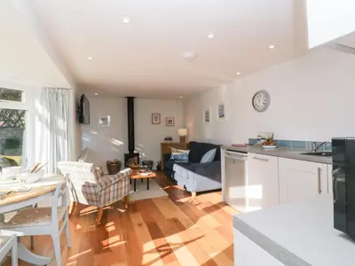 a kitchen and living room with a table and chairs at Old Kiln Cottage in Dumfries