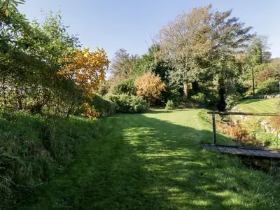 a path in a park with trees and a bench at Old Kiln Cottage in Dumfries