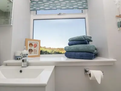a bathroom with a sink and a window and towels at Old Kiln Cottage in Dumfries