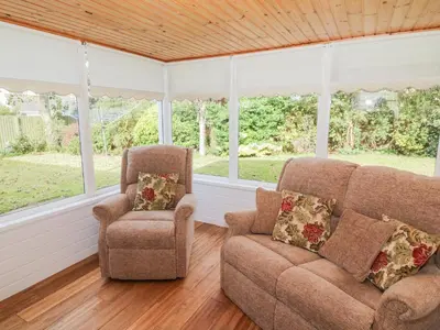 two chairs and a couch in a room with windows at Honesty Cottage in Girvan