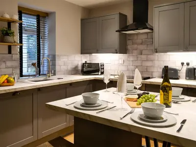 a kitchen with a table with plates and wine glasses at Terraughtie Cottage East-Uk31767 in Terreglestown