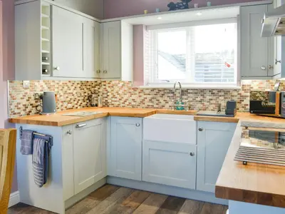 a kitchen with white cabinets and a window at Broomlands Cottage in Beattock