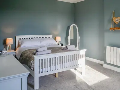 a bedroom with a white bed and a mirror at Broomlands Cottage in Beattock