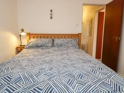a bed with a blue and white comforter in a bedroom at Oak View in Keswick