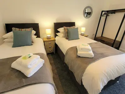 two beds in a room with towels on them at Garrarie Cottage in Monreith