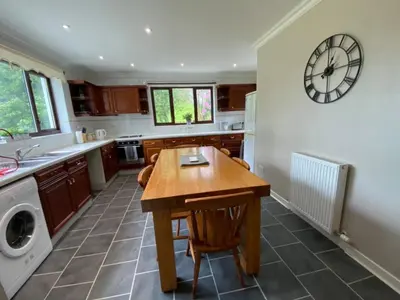 a kitchen with a table and a clock on the wall at West Lodge - Uk7137 in Newton Stewart