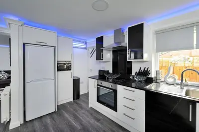a kitchen with white cabinets and black counter tops at Four Oaks House in Carlisle