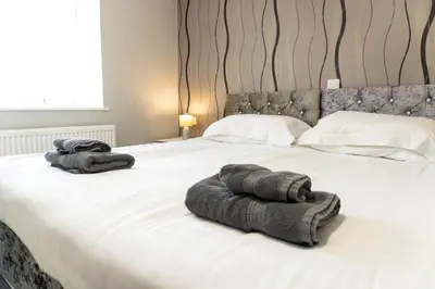 a bedroom with a large bed with towels on it at Four Oaks House in Carlisle