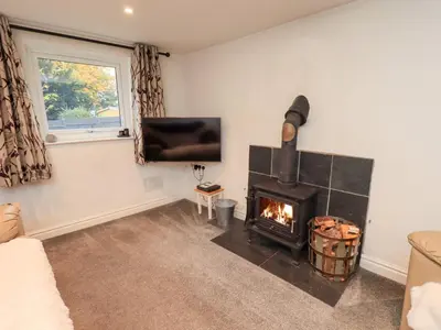 a living room with a fireplace and a tv at Kiln How in Keswick
