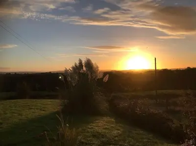 a sunset in a field with the sun in the sky at Shepherds Hut-hot tub hire-dog friendly-views in Dumfries